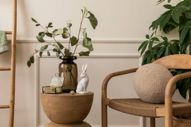 Spring composition of easter living room interior with wooden coffee table, glass vase with leaves, white bunny easter, stylish chair, round pillow and personal accessories. Home decor. Template. composición primaveral del interior de la sala de estar de pascua con mesa de centro de madera, jarrón de vidrio con hojas, pascua de conejo blanco, silla elegante, almohada redonda y accesorios personales. decoración del hogar. plantilla.
