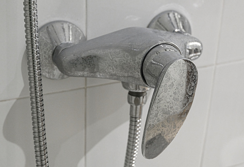 Close-up of a calcified faucet in the shower (limescale).