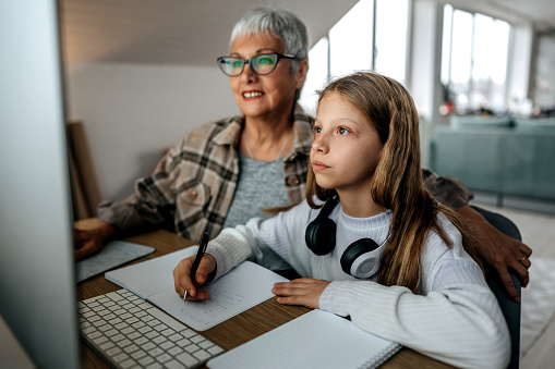 Grandmother helping granddaughter with homework while she's studying at home