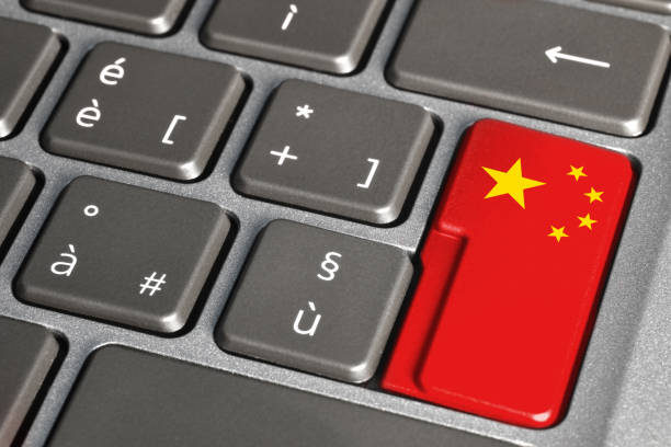 Button painted with the Chinese flag on grey laptop keyboard. Close-up view of flag of China on keyboard. stock photo