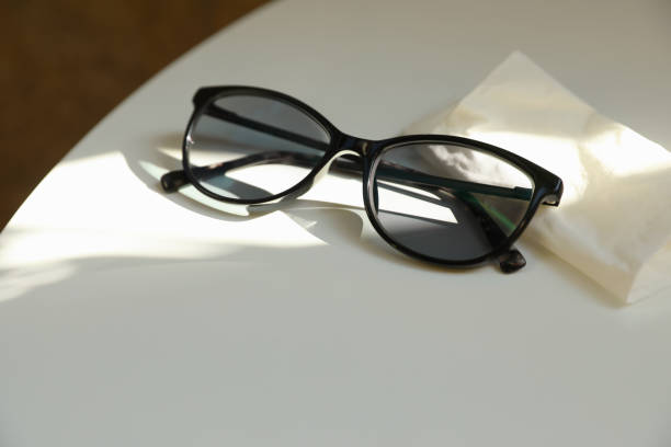 istock Stylish black eye glasses and cloth on white table. Space for text 1467011403