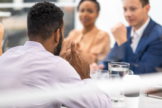 istock African american man sitting at conference room table with colleagues, back side view 1467012450