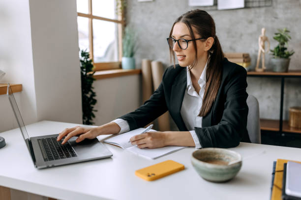 istock Young beautiful well dressed woman using laptop at her home office 1467013111