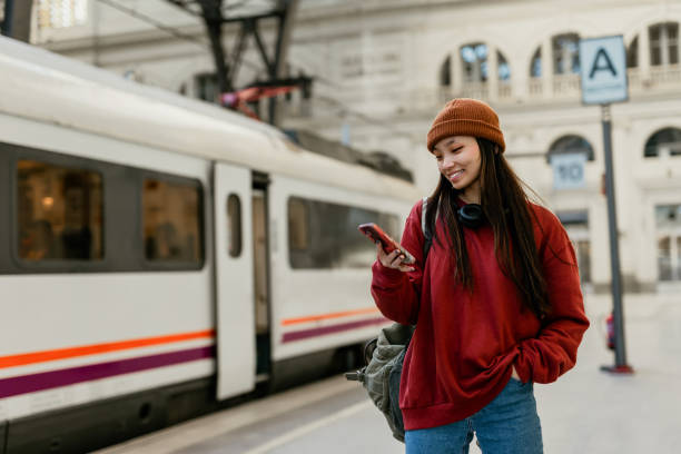 joven mujer asiática hipster usando un teléfono inteligente en la estación de tren - urban scene women adventure city fotografías e imágenes de stock