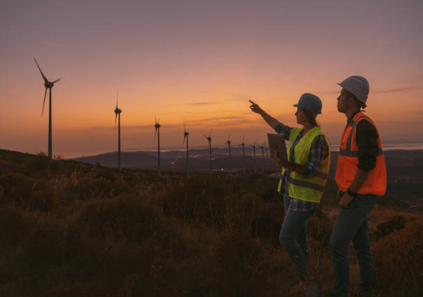 istock Young maintenance engineer team working in wind turbine farm at sunset 1467016473