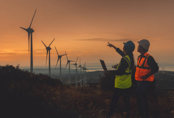 istock Young maintenance engineer team working in wind turbine farm at sunset 1467016732