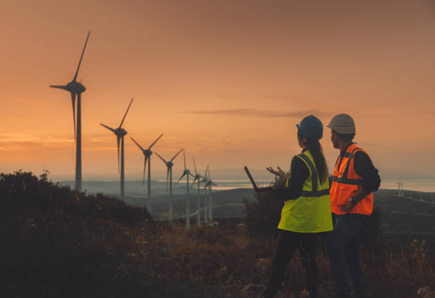 istock Young maintenance engineer team working in wind turbine farm at sunset 1467016753