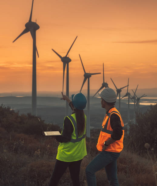 istock Young maintenance engineer team working in wind turbine farm at sunset 1467016839