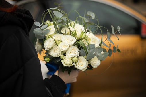 Bouquet of roses for bride. White flowers. Beautiful bouquet in hand of man. Feminine decoration.