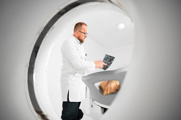 Doctor holding and explaining results of MRI to female patient. Medical computed tomography or MRI scanner. Doctor holding and explaining results of MRI. Woman patient lying on couch. Concept of medicine, healthcare and modern diagnostics. x ray results stock pictures, royalty-free photos & images
