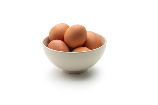 High angle view of a bowl with brown eggs, isolated on white background.