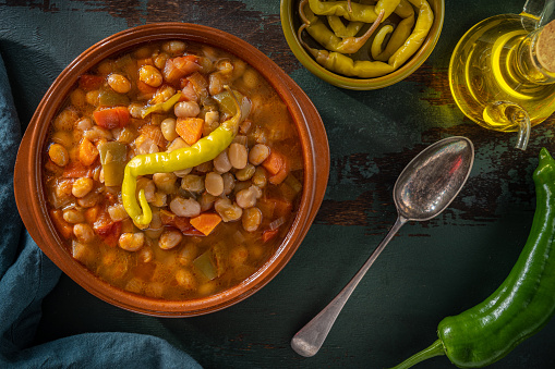 Pochas a la Navarra Spain white beans traditional stew with peppers and chili on a clay plate, Mediterranean food vegan plant based.