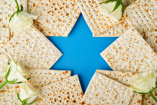 유월절 축하 개념입니다. 파란색 배경에 matzah, 흰색과 노란색 장미, 키파와 호두로 만든 다윗의 푸른 별. 전통적인 의식 유대인 유월절 음식. 유월절 유대인 휴일. 모형 - passover 뉴스 사진 이미지