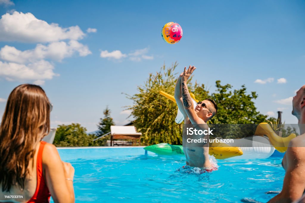 Group Of Friends Playing Volleyball In The Swimming Pool Group of beautiful young friends playing volleyball in the swimming pool in summer. Beach Ball Stock Photo