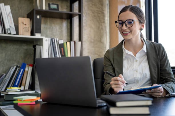 istock Young businesswoman with glasses working on document and laptop computer at office. 1467034558