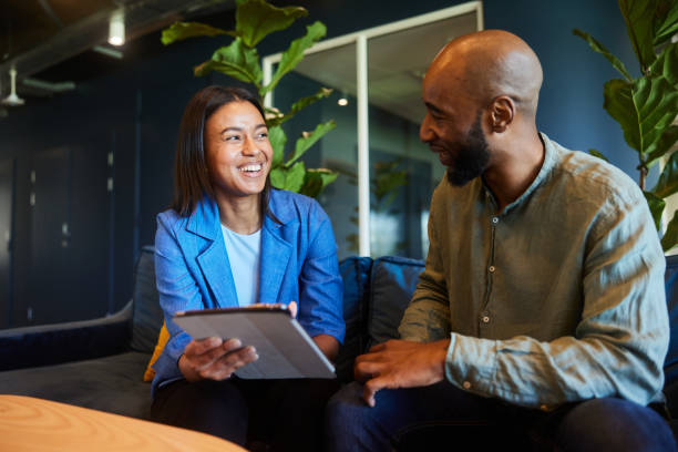 istock Laughing businesspeople working on a tablet on an office sofa 1467034599