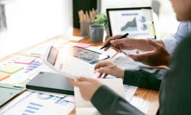 istock Two business people point to graphs and charts on tablet to analyze data, balance sheet, account and net profit to plan new sales strategies 1467035441