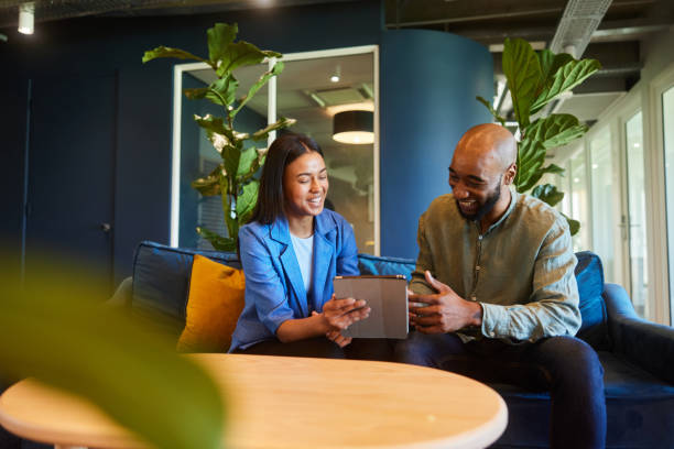 istock Businesspeople laughing while working on a tablet on an office sofa 1467036139