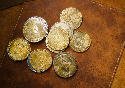 Antalya, Turkey - January 29, 2023: Close up shot of Bitcoin and alt coins cryptocurrency over dark leather background