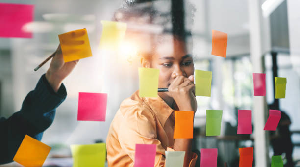 istock Young businesswoman creative team using sticky notes in glass wall to writing strategy business plan to development grow to success. 1467037925