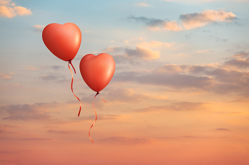 Heart shaped bred balloons couple on colorful clouds sunset sky. This file is cleaned and retouched.