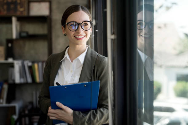 istock Pensive businesswoman in glasses holding file folder looking through window while working in office. 1467040749
