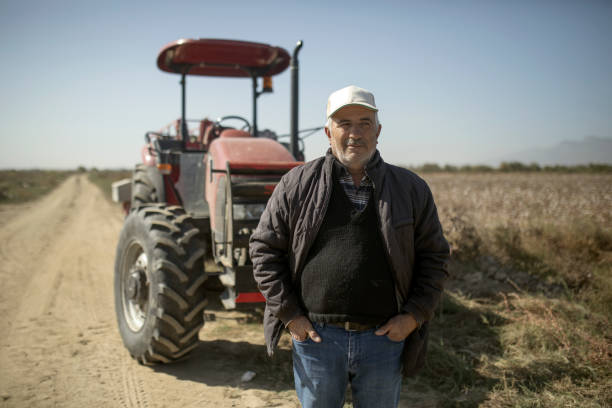 A royalty free image from the farming industry of a discouraged farmer in a field in front of a tractor.