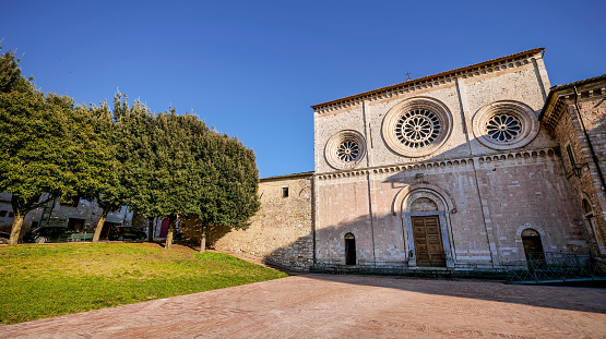 The beautiful facade of the Abbey Church of San Pietro in the medieval heart of Assisi in Umbria, central Italy. Built in Romanesque and Gothic style in the 10th century by the Benedictines, the facade was made of red stone from the nearby Monte Subasio. It has a rectangular shape with three entrance portals and three rose windows. The large central portal is surmounted by an arch and a larger rose window. Famous for being the city of San Francesco and Santa Chiara (St Francis and St Clare), Assisi is recognized in the world as a place of spirituality and peace between all peoples and different confessions. The Umbria region, considered the green lung of Italy for its wooded mountains, is characterized by a perfect integration between nature and the presence of man, in a context of environmental sustainability and healthy life. In addition to its immense artistic and historical heritage, Umbria is famous for its food and wine production and for the high quality of the olive oil produced in these lands. Since 2000 the Franciscan sites of Assisi have been declared a World Heritage Site by UNESCO. Super wide angle image in 16:9 format and high definition quality.