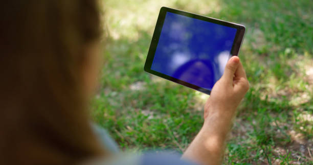 istock Unknown hands holding tablet on nature. Unrecognizable man have gadget on picnic 1467044627