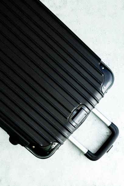 istock black suitcase lay flat,Black luggage set on dark background, top view image, flat lay composition. Travel minimalist concept, black and dark classic baggage mockup, small and big. Suitcase accessory set, journey concept. 1467046898