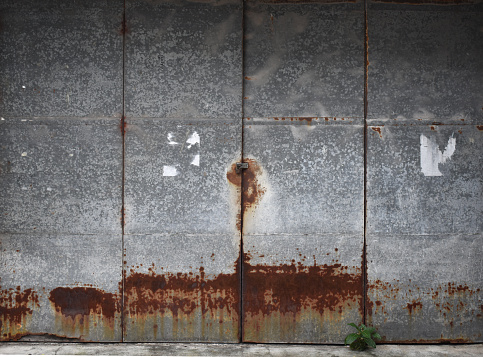 A large sheet of metal was assembled to form the door. which is rusty , metal background