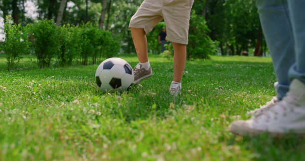 istock Unknown boy legs making soccer exercise closeup. Son training football with dad. 1467052829
