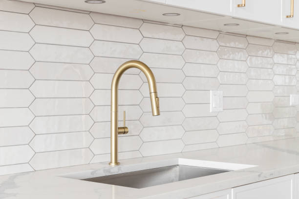 istock A kitchen detail with white cabinets, gold faucet, and tiled backsplash. 1467058565