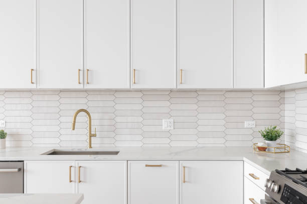 istock A kitchen detail with white cabinets, gold faucet, and tiled backsplash. 1467058752