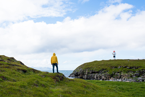 Men in yellow hoodie outdoor enjoys the scenic view of the fjord. Stunning beauty nature. Harmony, relax lifestyle. Travel, adventure. Sense of freedom. Explore North Norway. Summer in Scandinavia