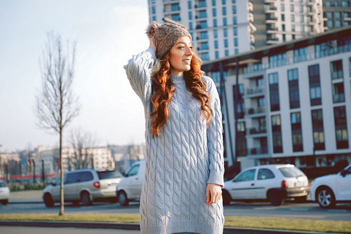 Beautiful casual woman outdoor wearing blue sweater dress and cap hat, city concept