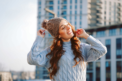 Beautiful casual woman outdoor wearing blue sweater dress and cap hat, city concept