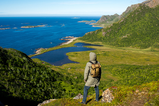 A man enjoy the scenic nature. Northern beauty panoramic view. Fjord, ocean and mountain landscape. Travel, adventure. Sense of freedom, relax lifestyle. Explore North Norway. Lofoten Islands