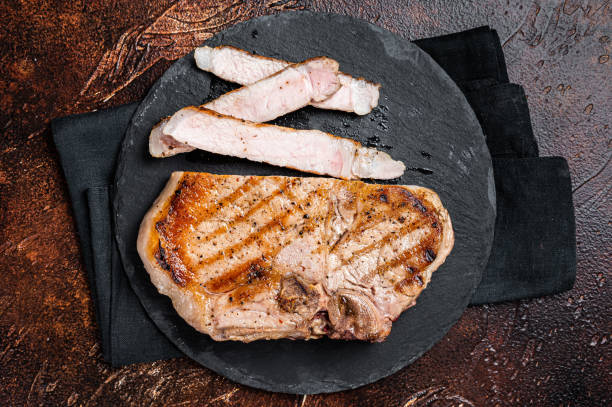 istock Roast BBQ pork Chop or T-bone meat steak sliced on a board. Dark background. Top view 1467067589