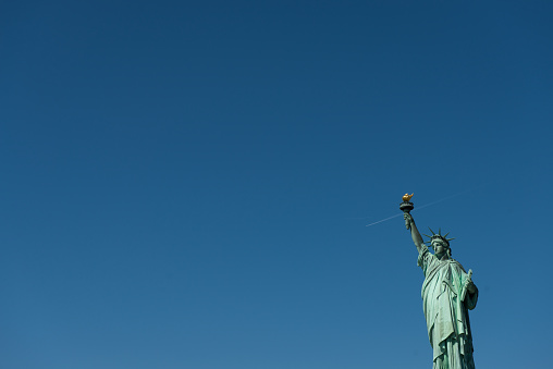 Statue of Liberty and blue skies and airplane jetstream