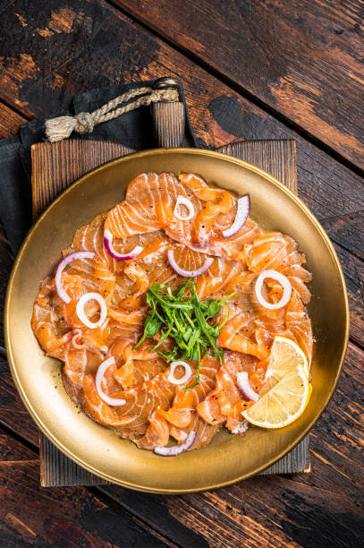 carpaccio di salmone italiano con cipolla e rucola servito su un piatto. sfondo in legno. vista dall'alto - smoked salmon cooking copy space food foto e immagini stock