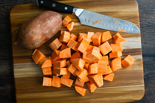 Prepped sweet potato chunks on a wooden cutting board