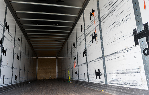 View of the inside of the rear of a huge empty freight truck with the rear doors open. Conceptual image about global human trafficking.