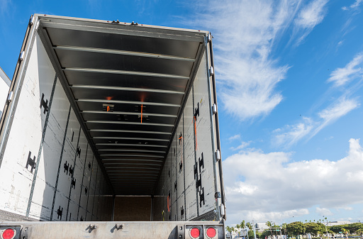 View of the inside of the rear of a huge empty freight truck with the rear doors open. Conceptual image about global human trafficking.