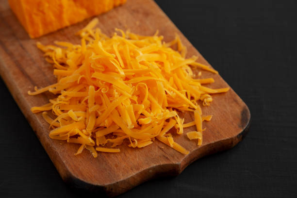 istock Shredded Sharp Cheddar Cheese on a rustic wooden board on a black surface, side view. Copy space. 1467079188