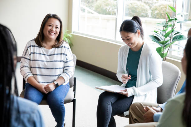 Adults discuss ideas while meeting for support group or counseling session stock photo