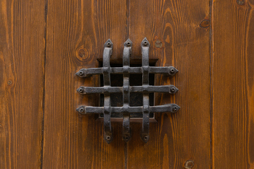 Detail of a wooden antique door with metal spikes.
