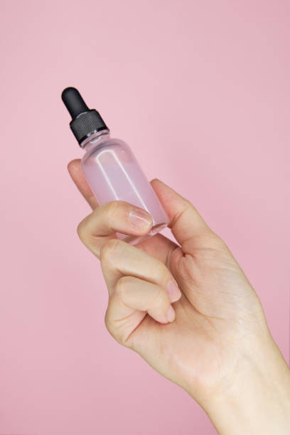 istock Female hands with pink serum in bottles on pink background 1467089907