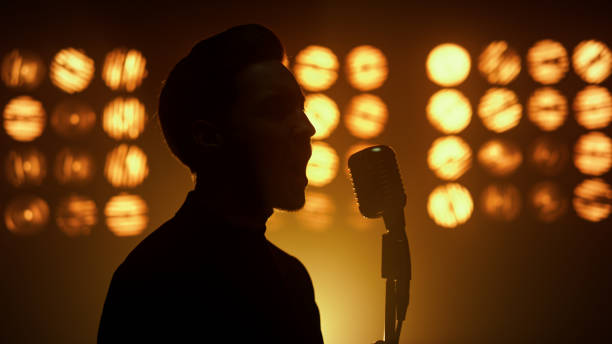 cantante dell'uomo che canta della silhouette usando il microfono sul primo piano della discoteca del palcoscenico dello spettacolo - microphone stage music popular music concert foto e immagini stock