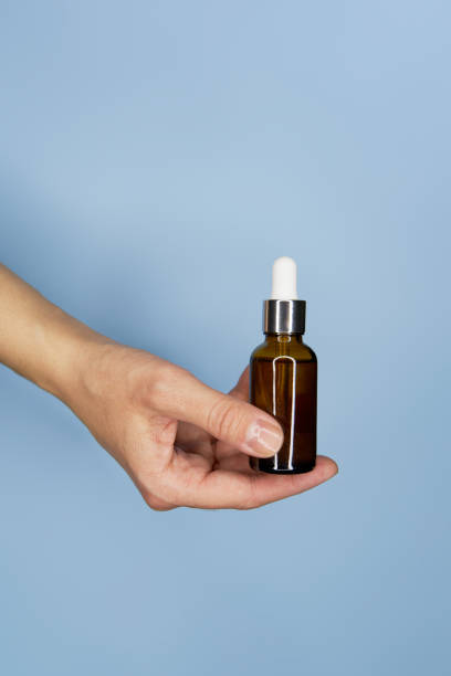 istock Female hands with serum in bottles on blue background 1467096612
